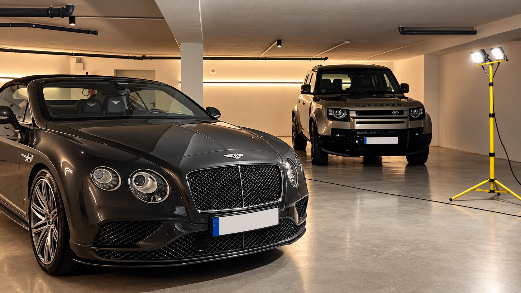 Bentley Continental and Land Rover Defender in a garage.